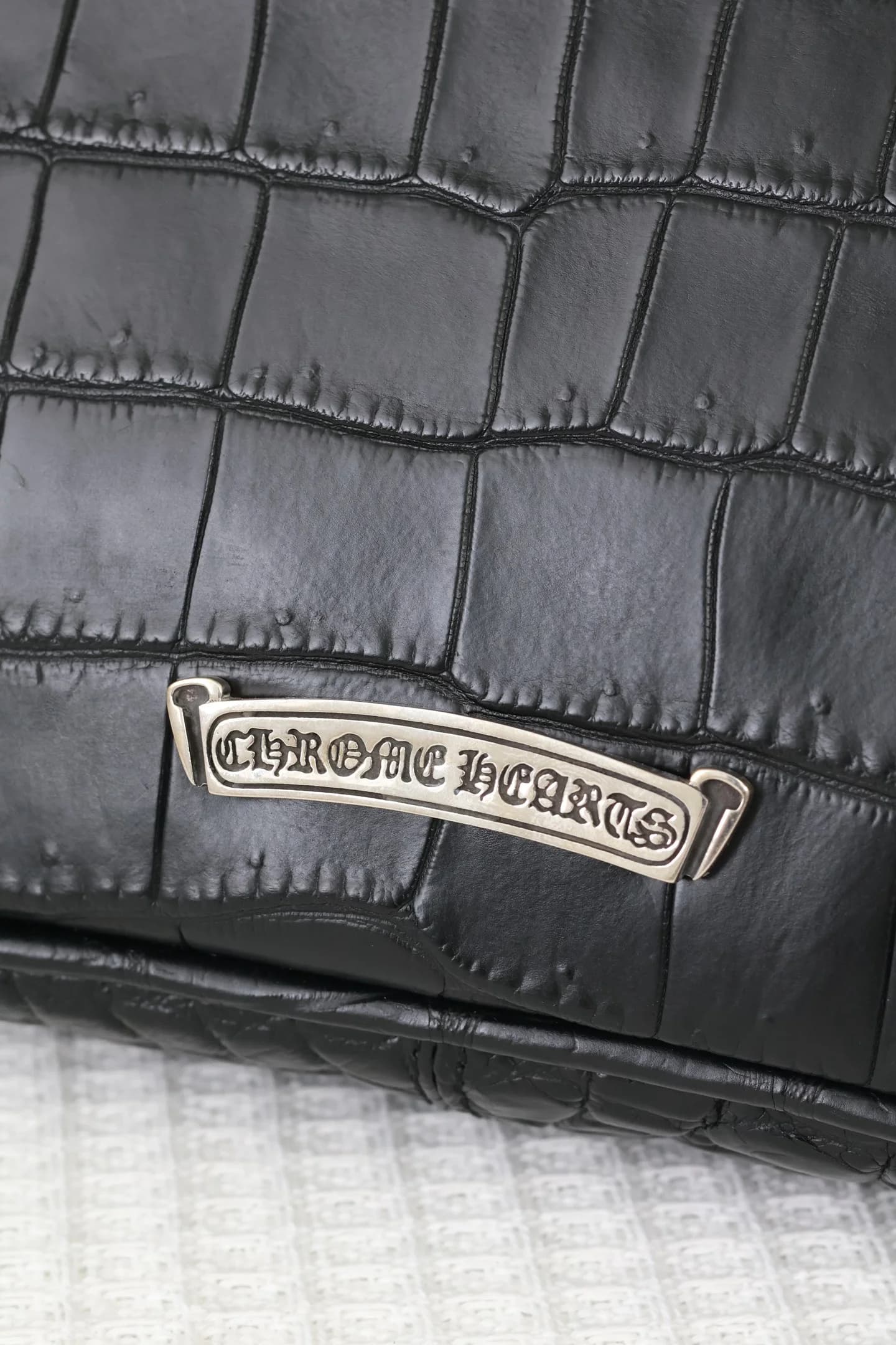 Серебряная плашка с гравировкой Chrome Hearts на задней панели сумки