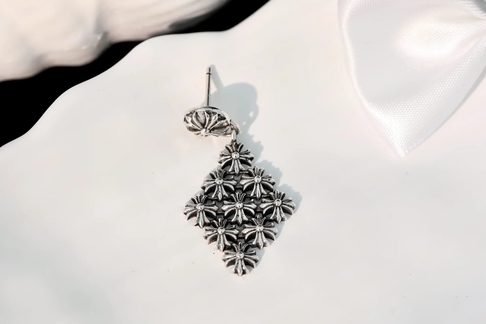 Одна серьга-пусет Chrome Hearts крупным планом на белой поверхности