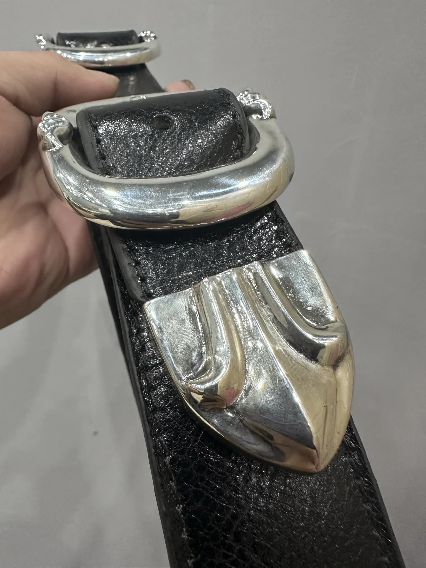 Крупный план массивной серебряной пряжки и фигурного наконечника ремня Chrome Hearts