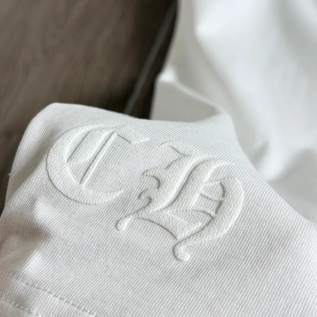 Деталь тиснения CH на белой футболке Chrome Hearts