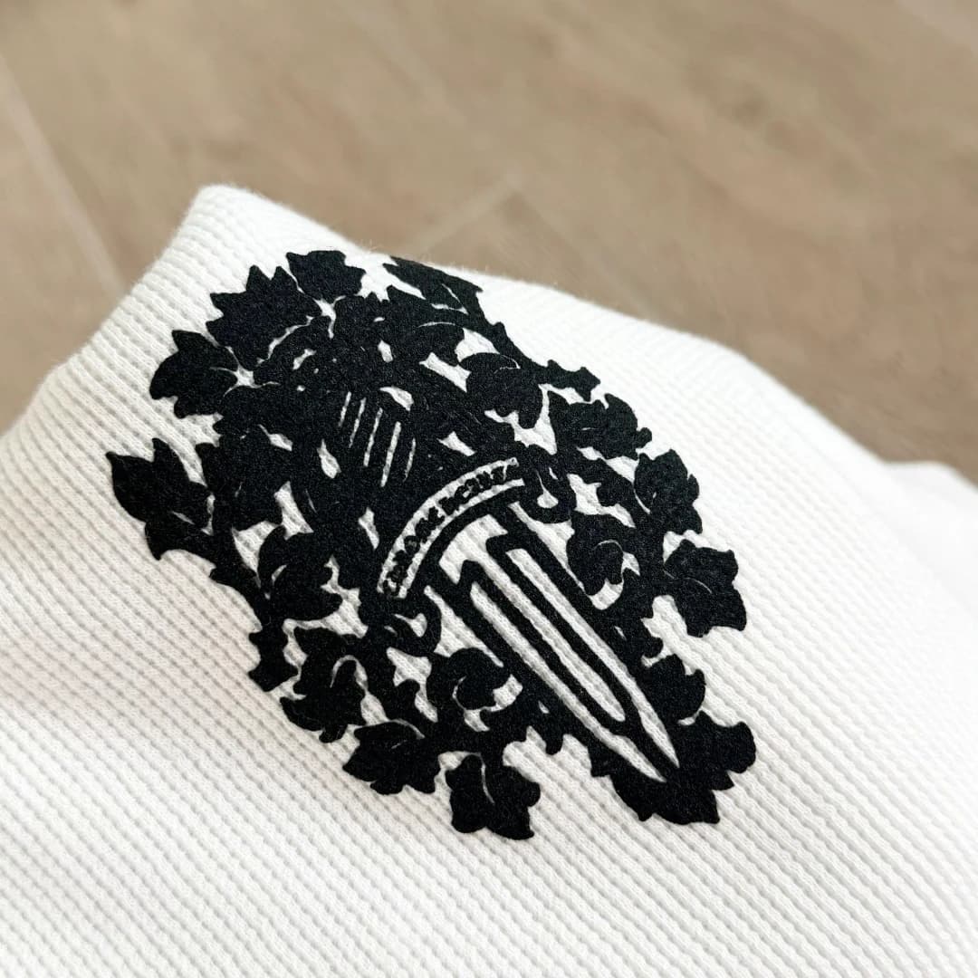 Крупный план черного принта с кинжалом на белом лонгсливе Chrome Hearts
