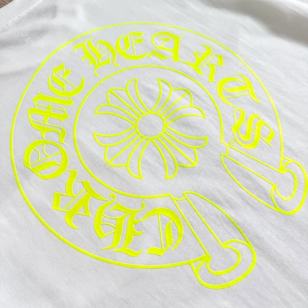 Деталь неонового принта на белой футболке Chrome Hearts