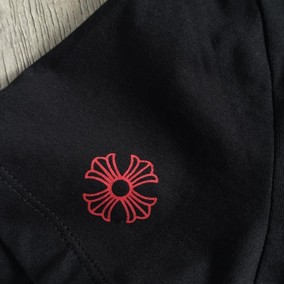 Красный фирменный крест на рукаве чёрной футболки Chrome Hearts