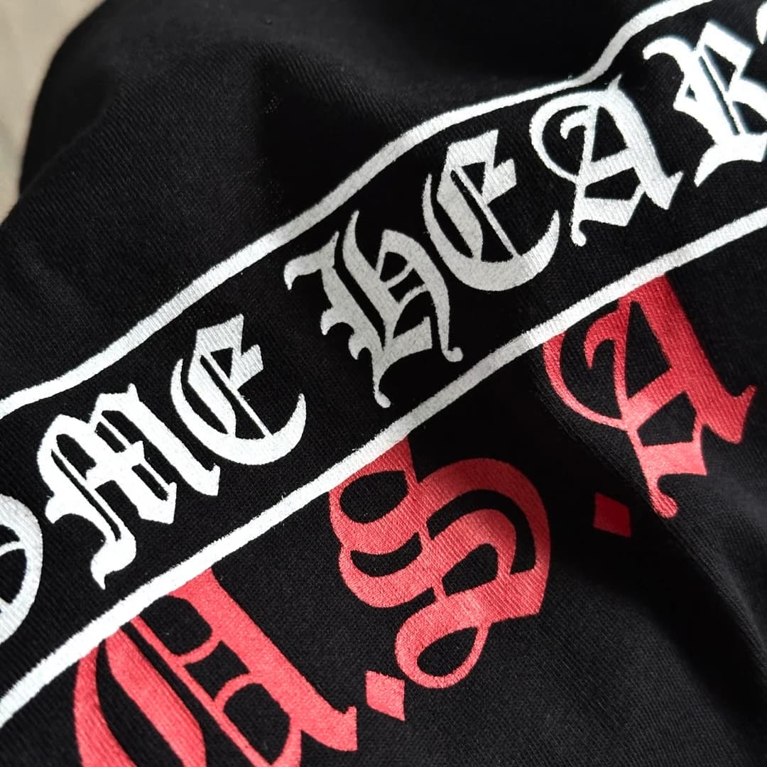 Крупный план принта Chrome Hearts U.S.A. на чёрной футболке