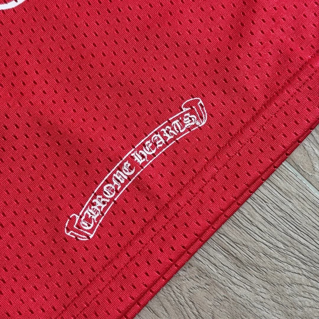 Деталь вышивки Chrome Hearts на нижней кромке красной футболки-джерси