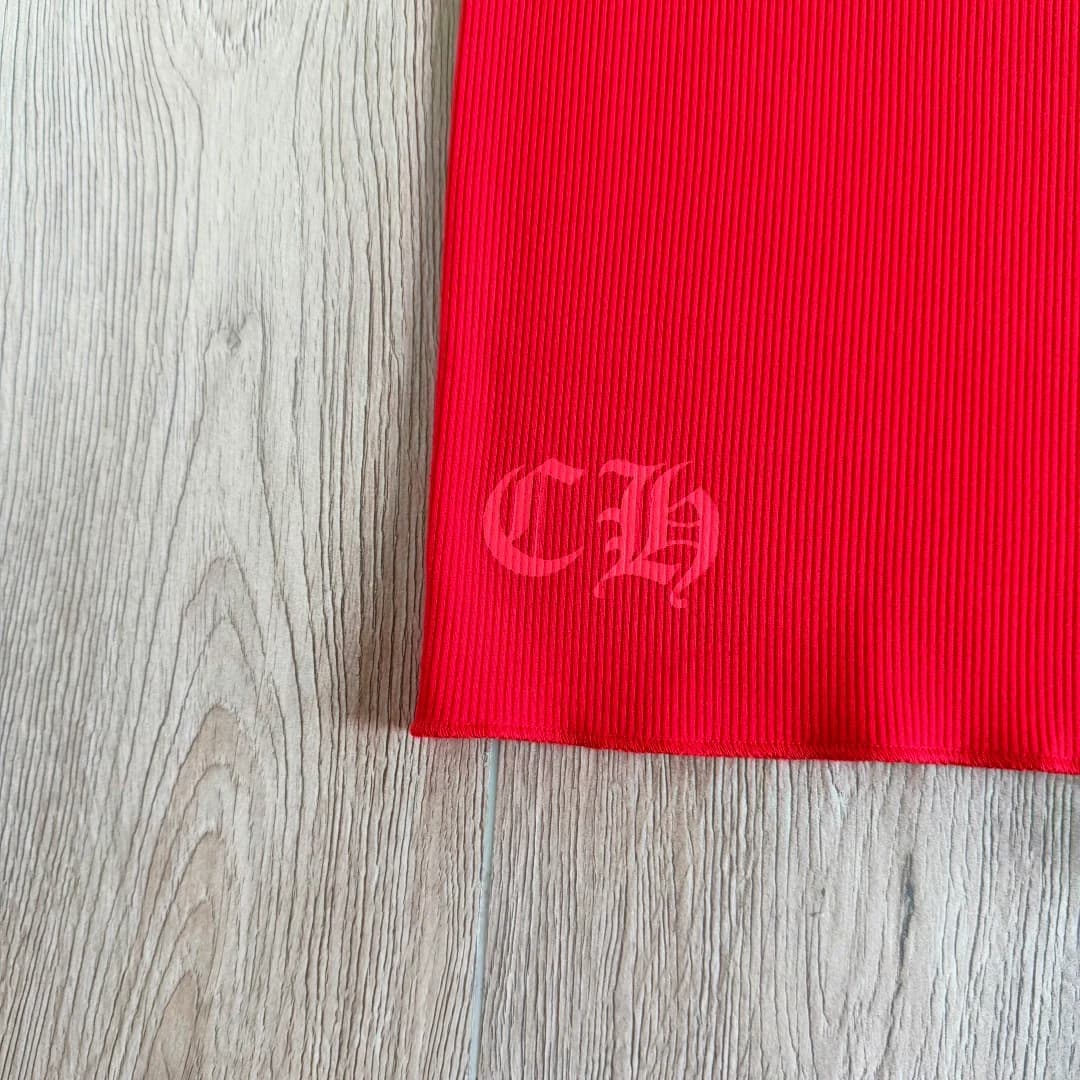 Деталь низа красного платья-майки Chrome Hearts с принтом CH