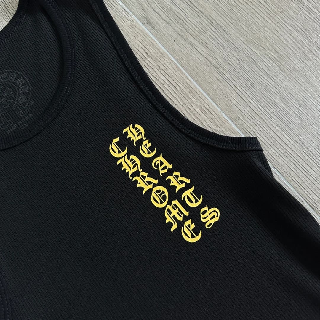 Крупный план желтого готического принта на груди майки Chrome Hearts