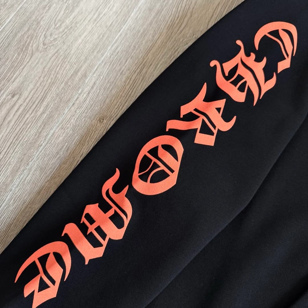 Крупный план оранжевого принта Chrome Hearts на рукаве