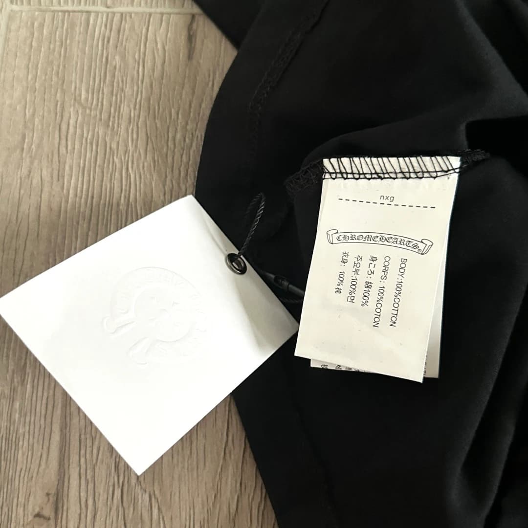 Бирка с составом ткани на черной футболке Chrome Hearts