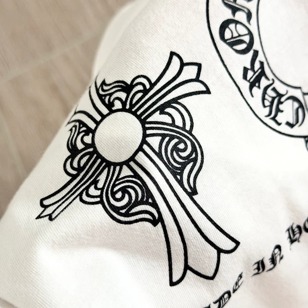 Крупный план принта с геральдическим крестом на белой футболке Chrome Hearts