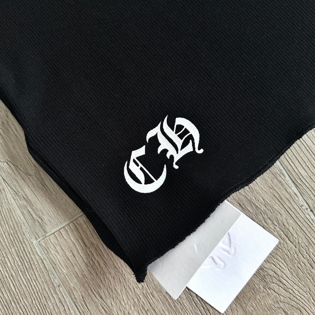 Деталь нижнего края черной майки Chrome Hearts с готическими буквами CH