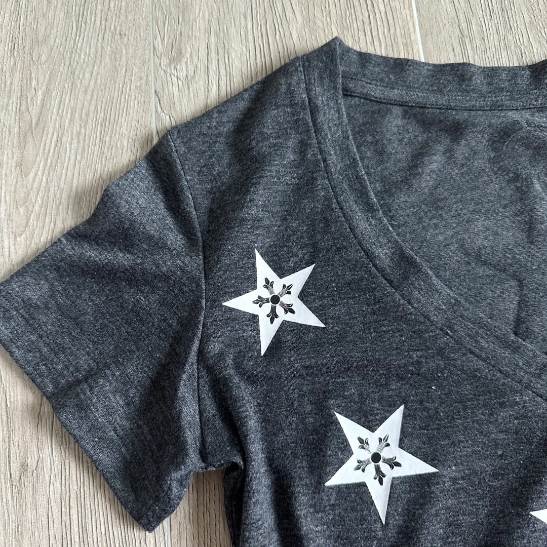 Крупный план принта в виде звезд на плече серой футболки Chrome Hearts