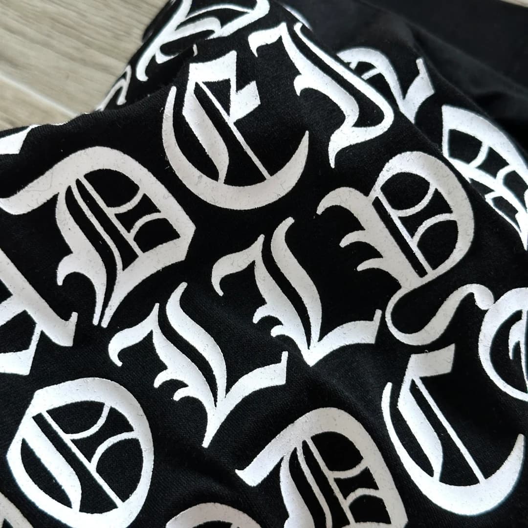Крупный план готического текстового принта на спине черной футболки Chrome Hearts