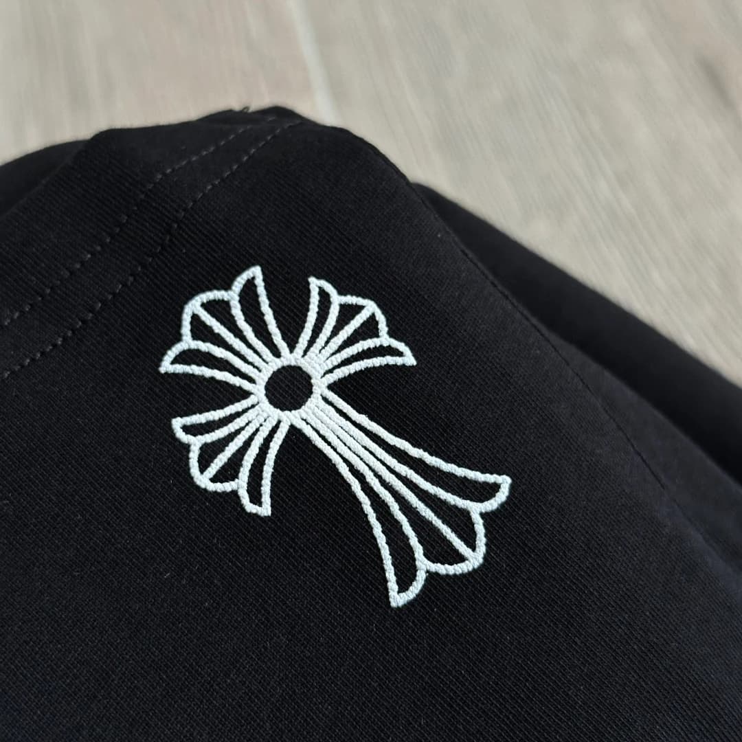 Деталь вышивки креста на черной футболке Chrome Hearts