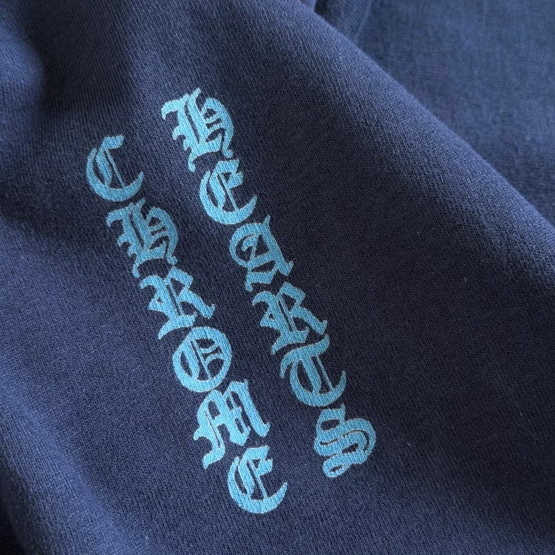 Деталь голубого текстового принта на груди футболки Chrome Hearts