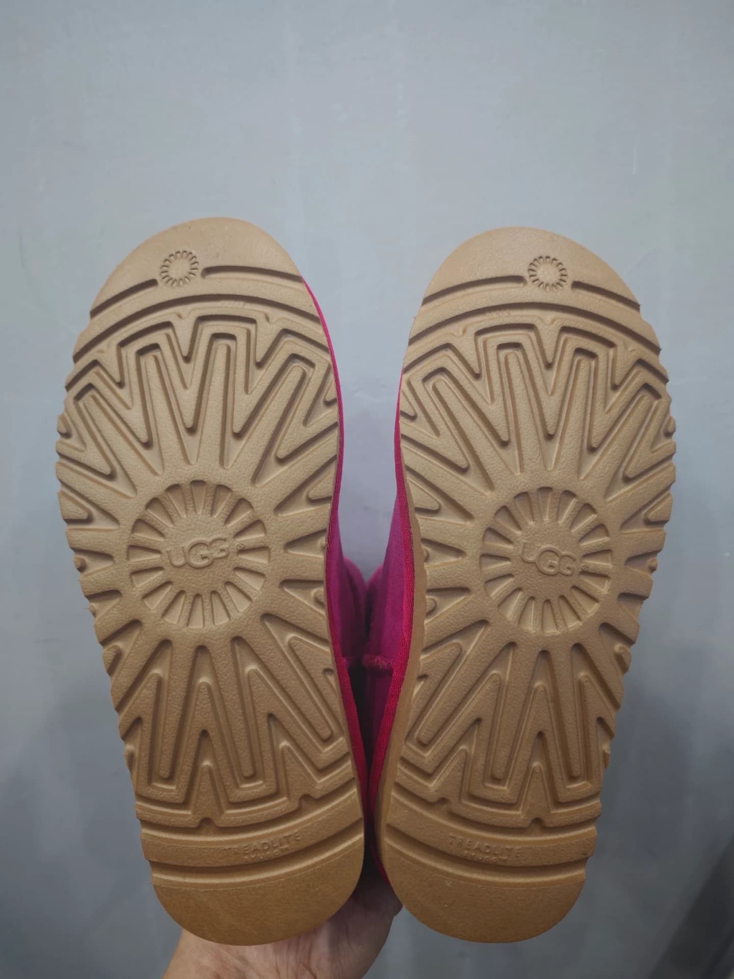 Бежевая рельефная подошва пары розовых угг UGG с фирменным рисунком протектора