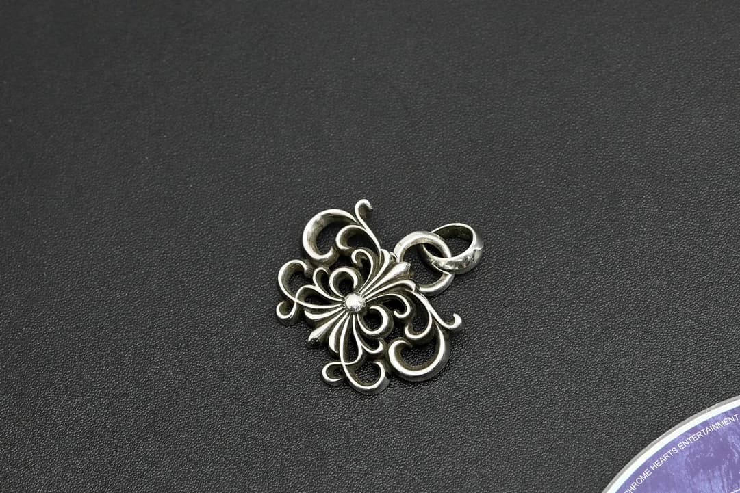 Серебряная фигурная подвеска под углом на тёмном фоне
