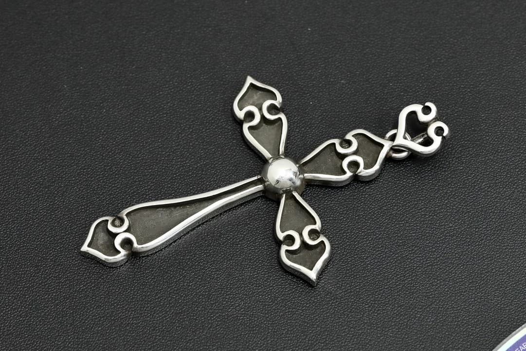 Крупный план серебряной подвески-креста с фигурной отделкой