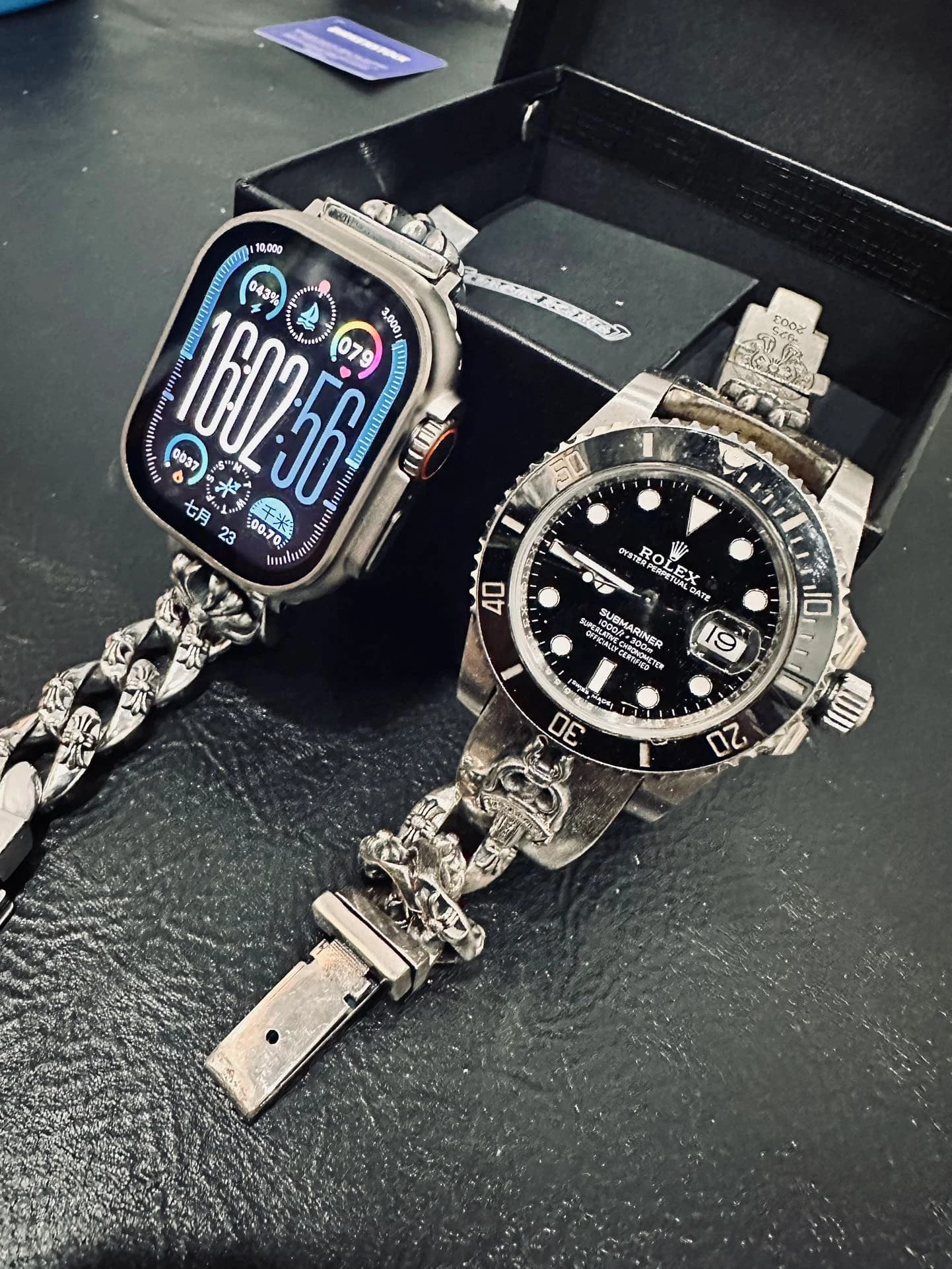 Серебряный ремешок для смарт-часов Chrome Hearts рядом с часами на черном фоне