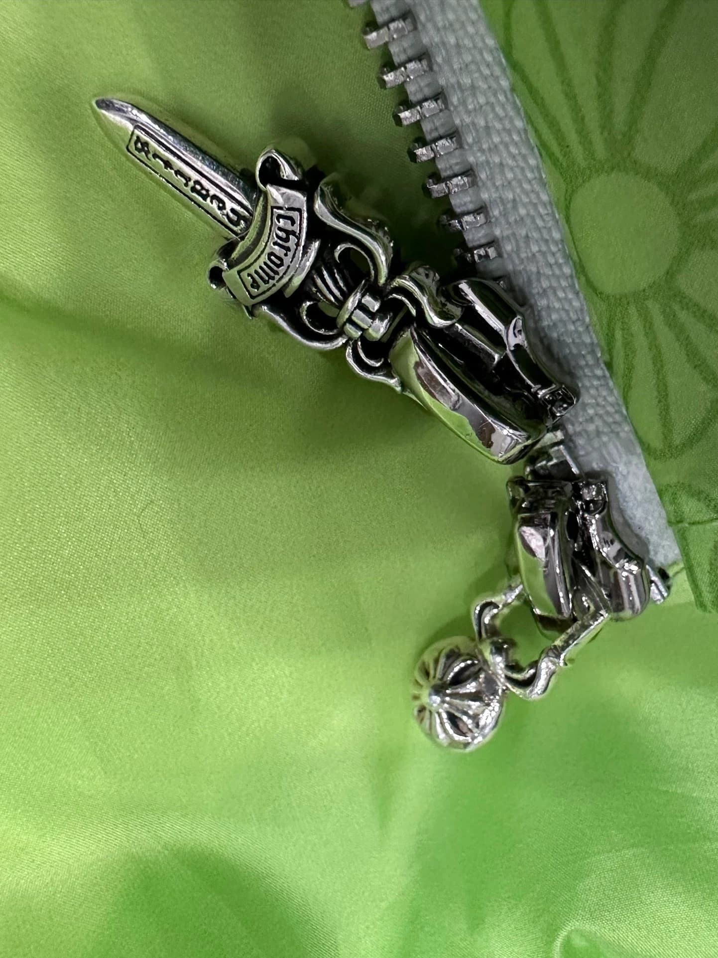 Серебряный пуллер молнии в форме кинжала на зеленом жилете Chrome Hearts