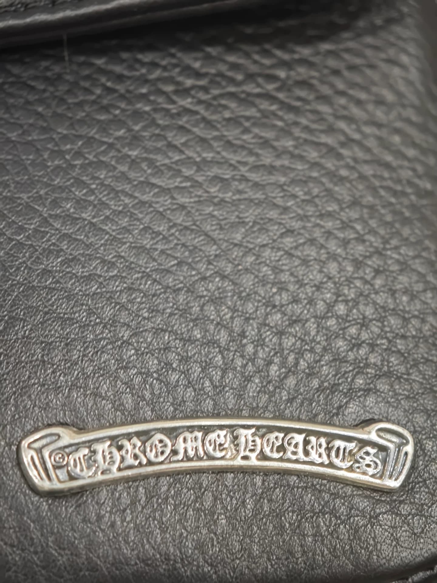 Крупный план серебряной плашки с гравировкой логотипа Chrome Hearts
