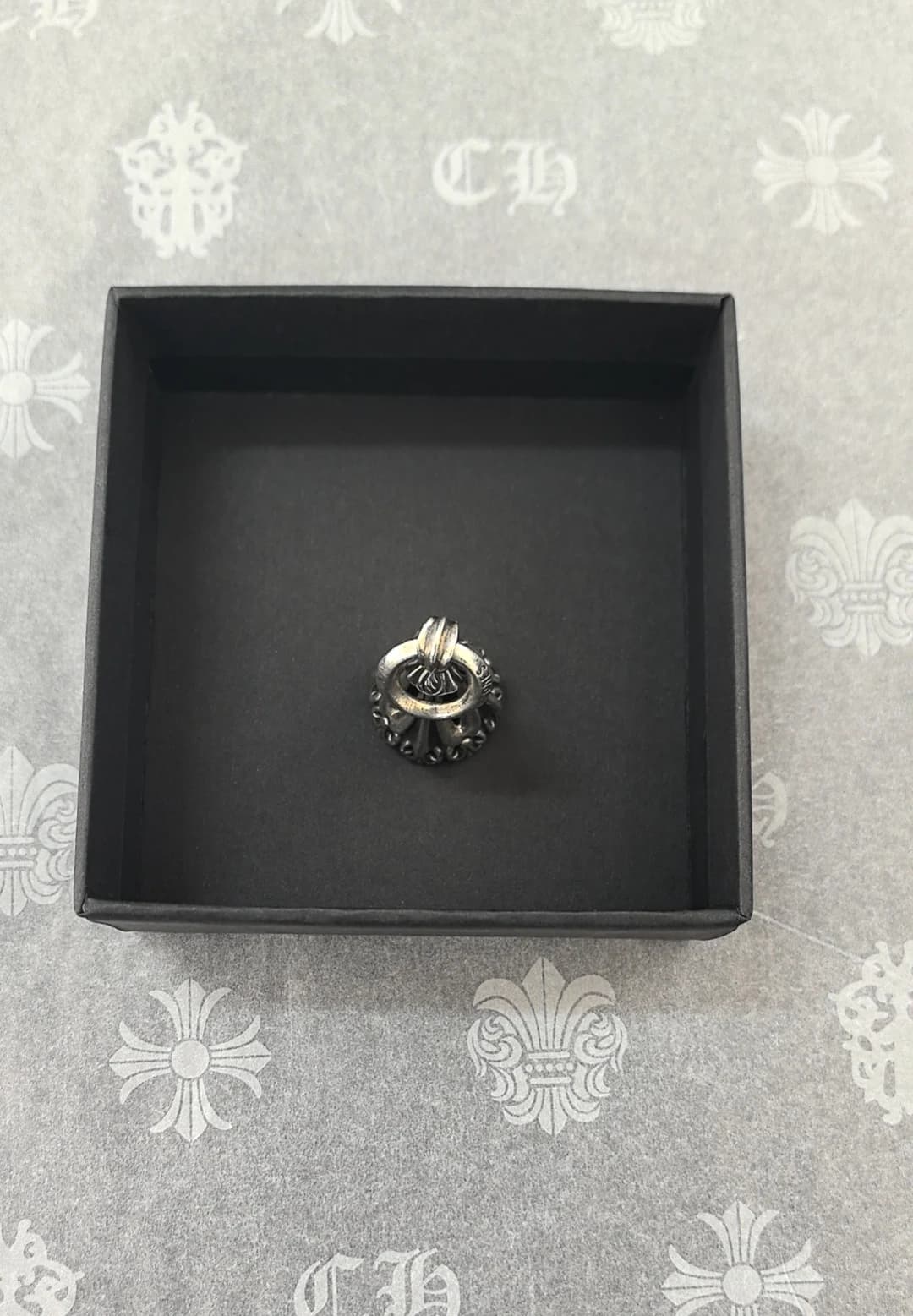 Вид сверху на серебряную подвеску Chrome Hearts Bell в коробке