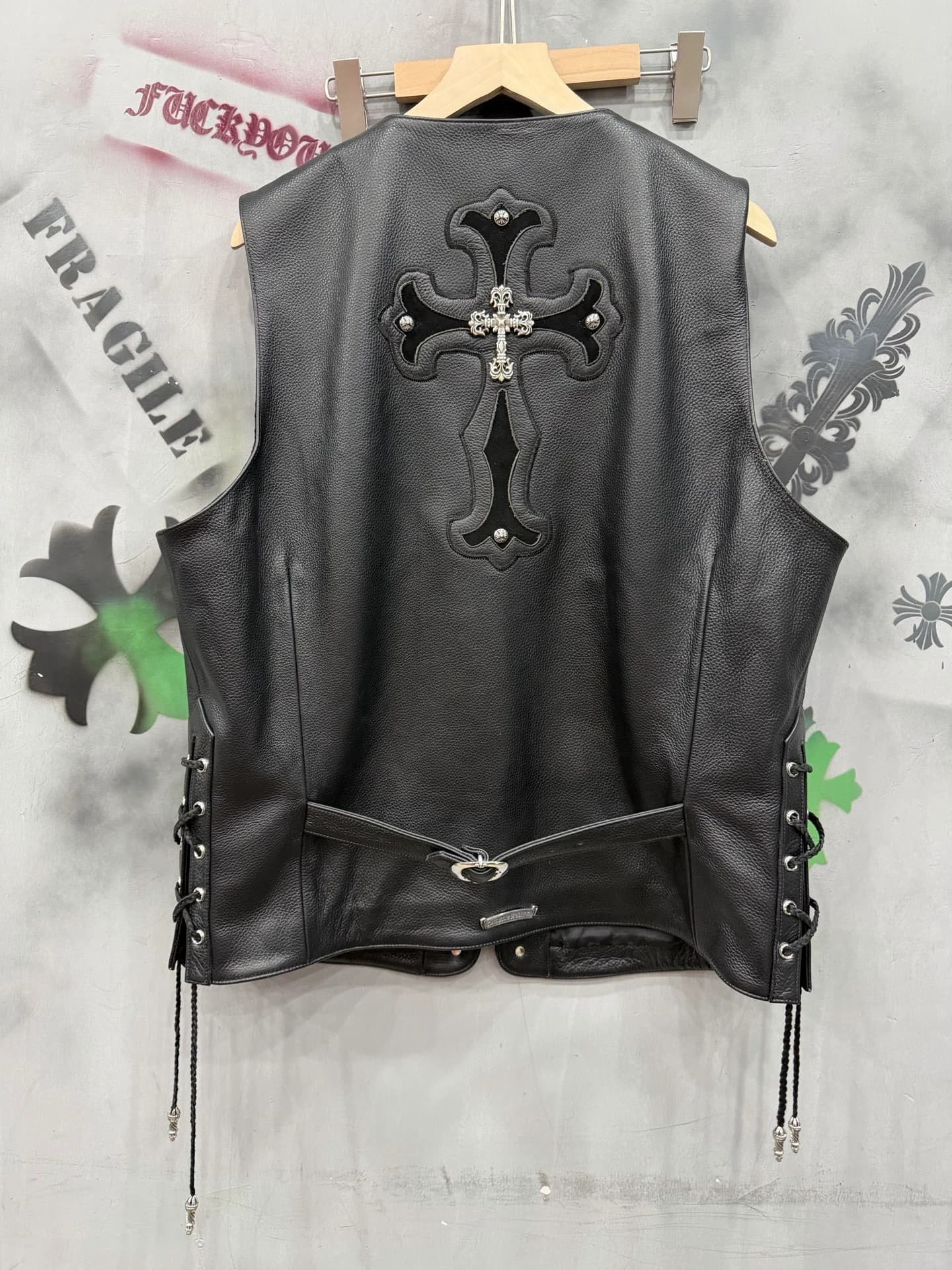 Вид сзади: черный кожаный жилет Chrome Hearts с нашивкой в виде креста и шнуровкой