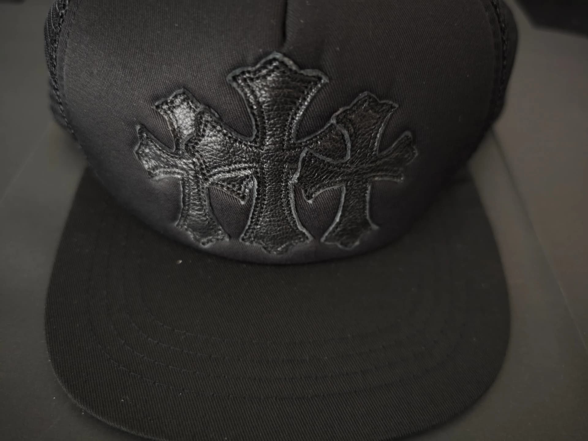Деталь черной бейсболки Chrome Hearts с черными кожаными патчами