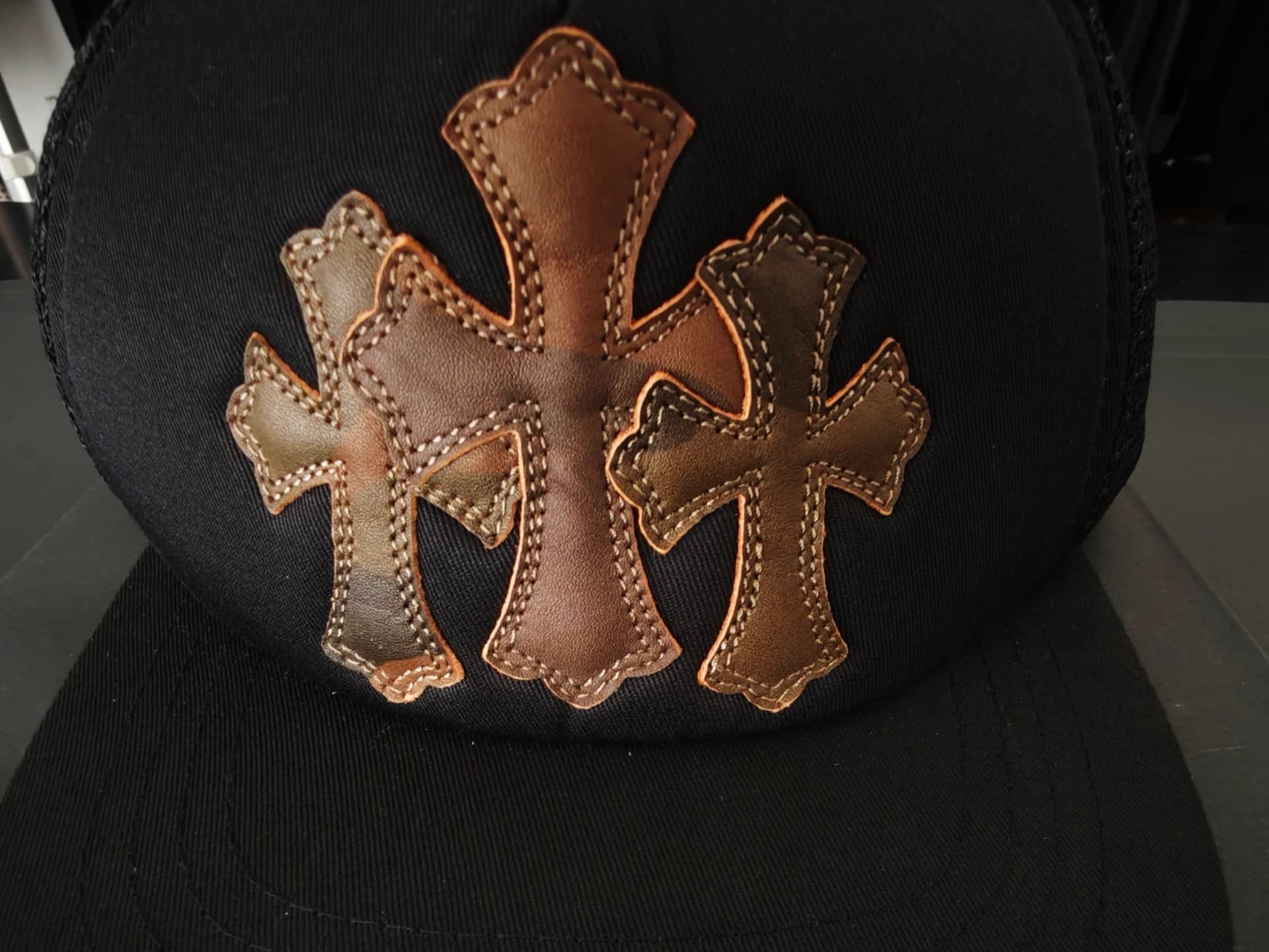 Деталь черной бейсболки Chrome Hearts с коричневыми кожаными патчами