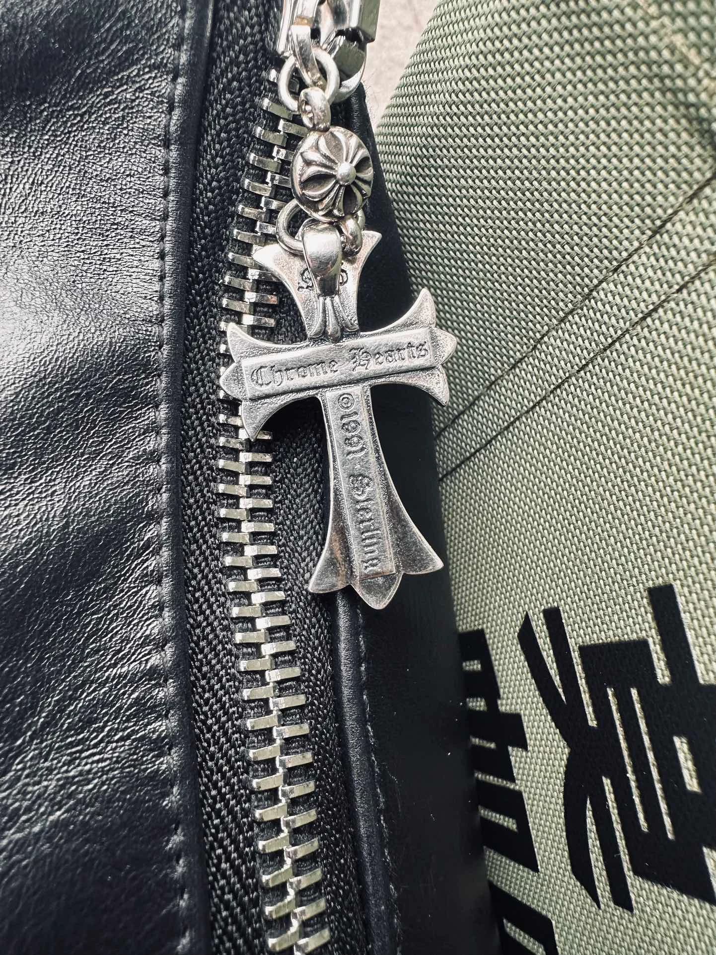 Крупный план серебряного бегунка с гравировкой Chrome Hearts на молнии