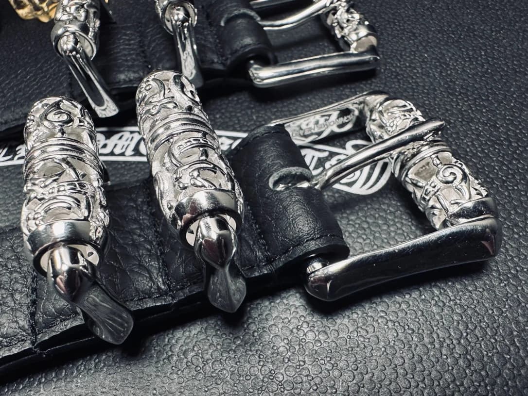 Крупный план серебряной пряжки и резных шлевок ремня Chrome Hearts