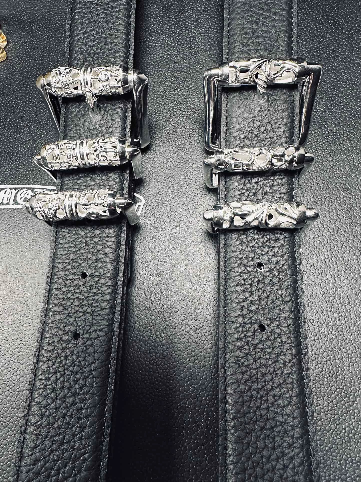 Вид на пряжки и полотно черных кожаных ремней Chrome Hearts с перфорацией