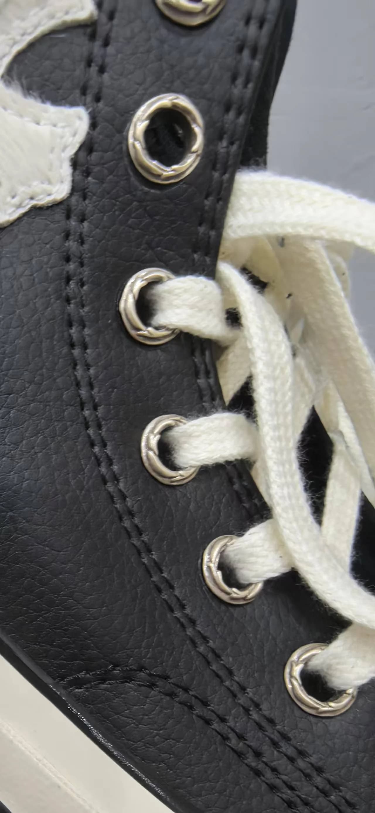 Крупный план кожаной текстуры и металлических люверсов кед Chrome Hearts x Converse