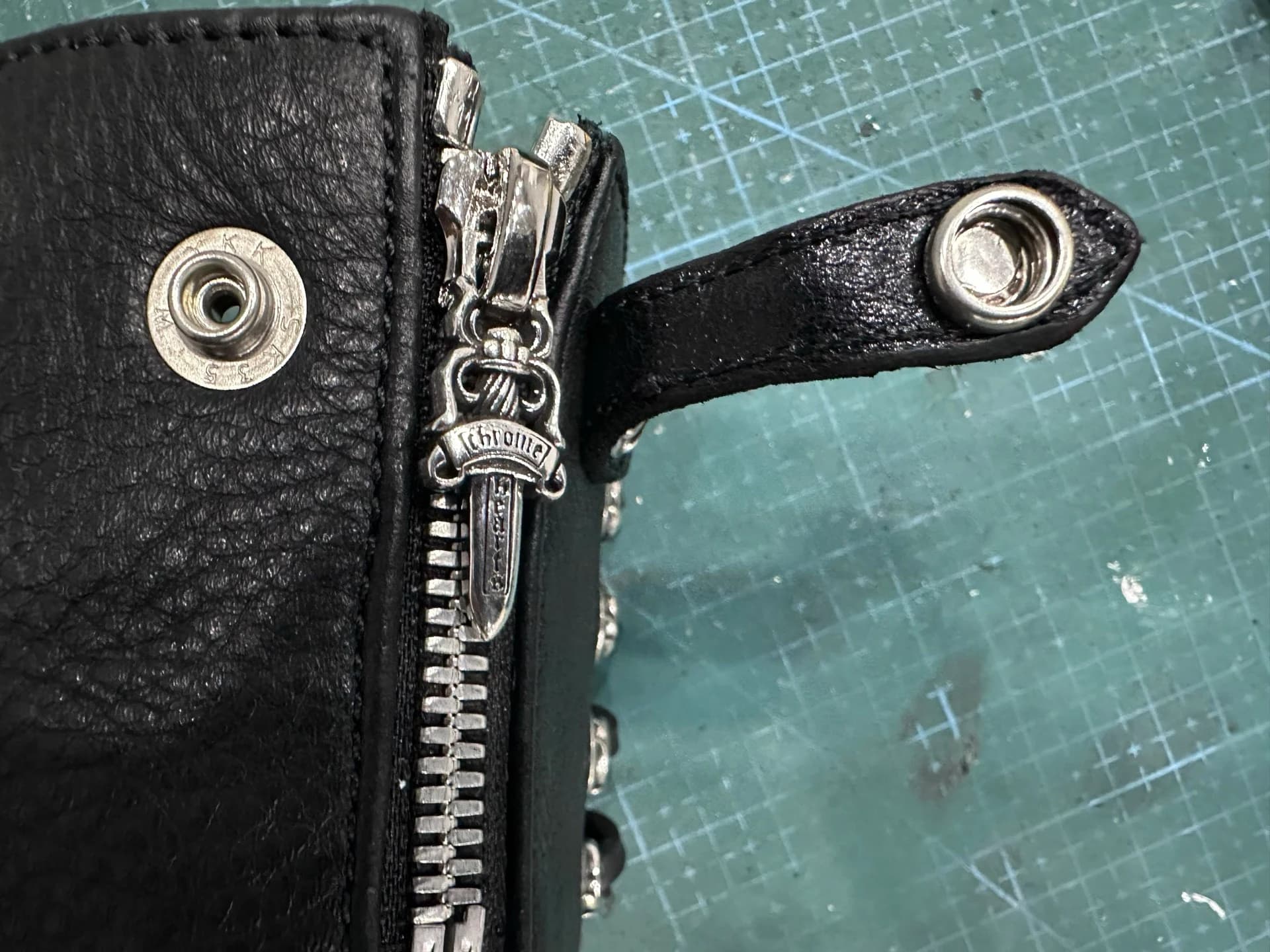 Крупный план застежки-молнии и металлической кнопки на напульснике Chrome Hearts