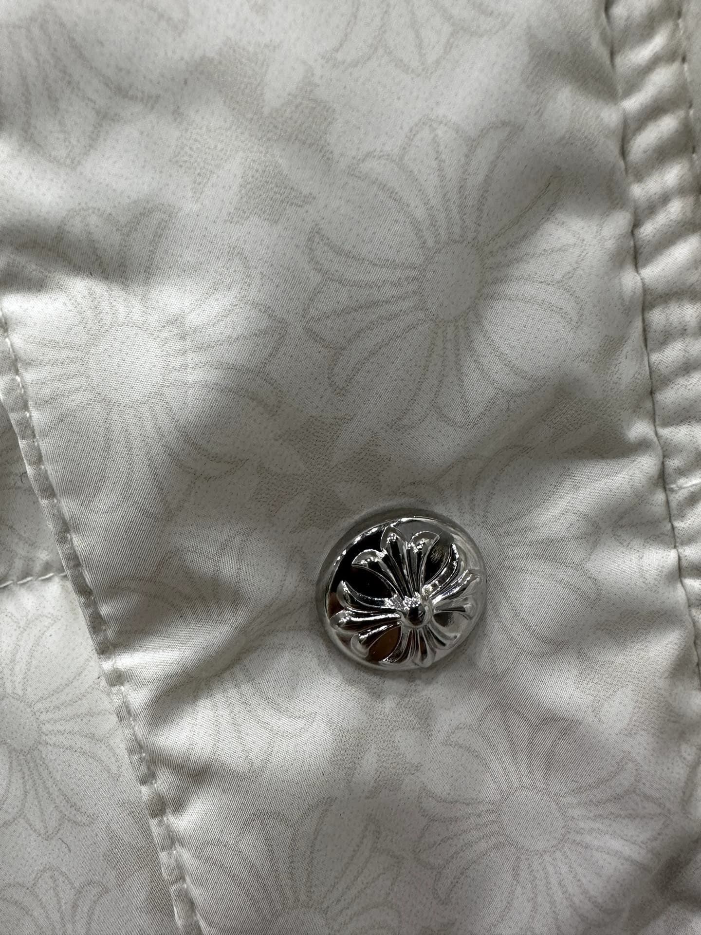 Деталь белого пуховика Chrome Hearts: серебряная кнопка с гравировкой