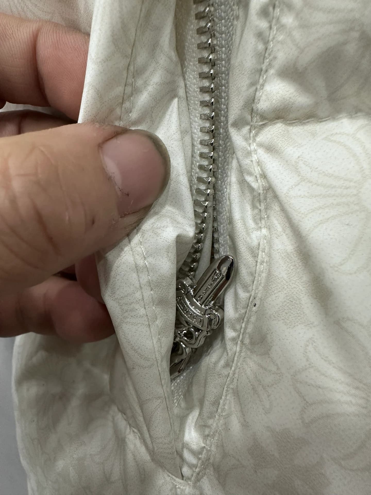 Деталь белого пуховика Chrome Hearts: молния с серебряным пуллером