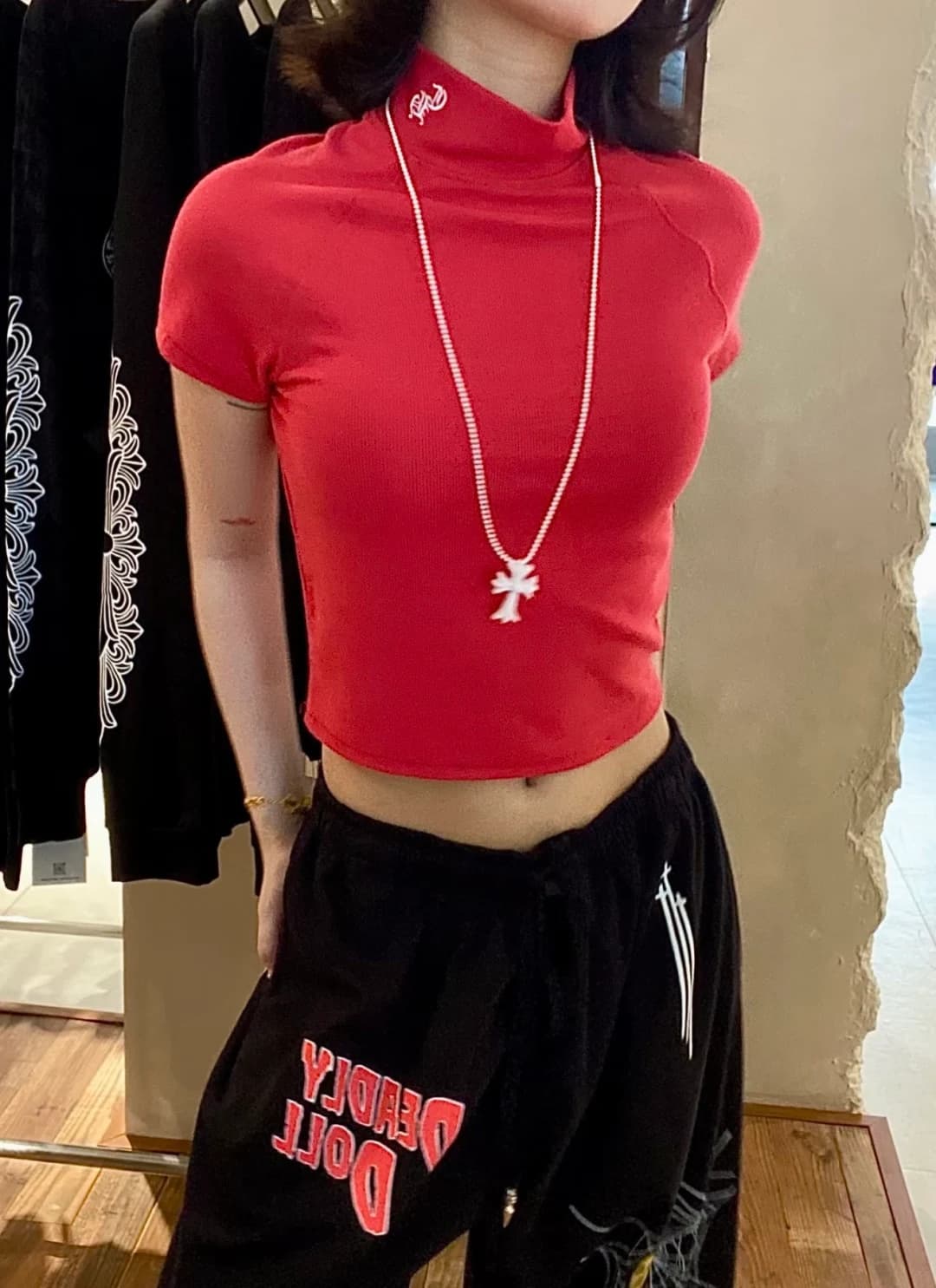 Девушка в красном топе Chrome Hearts и чёрных спортивных брюках, вид спереди