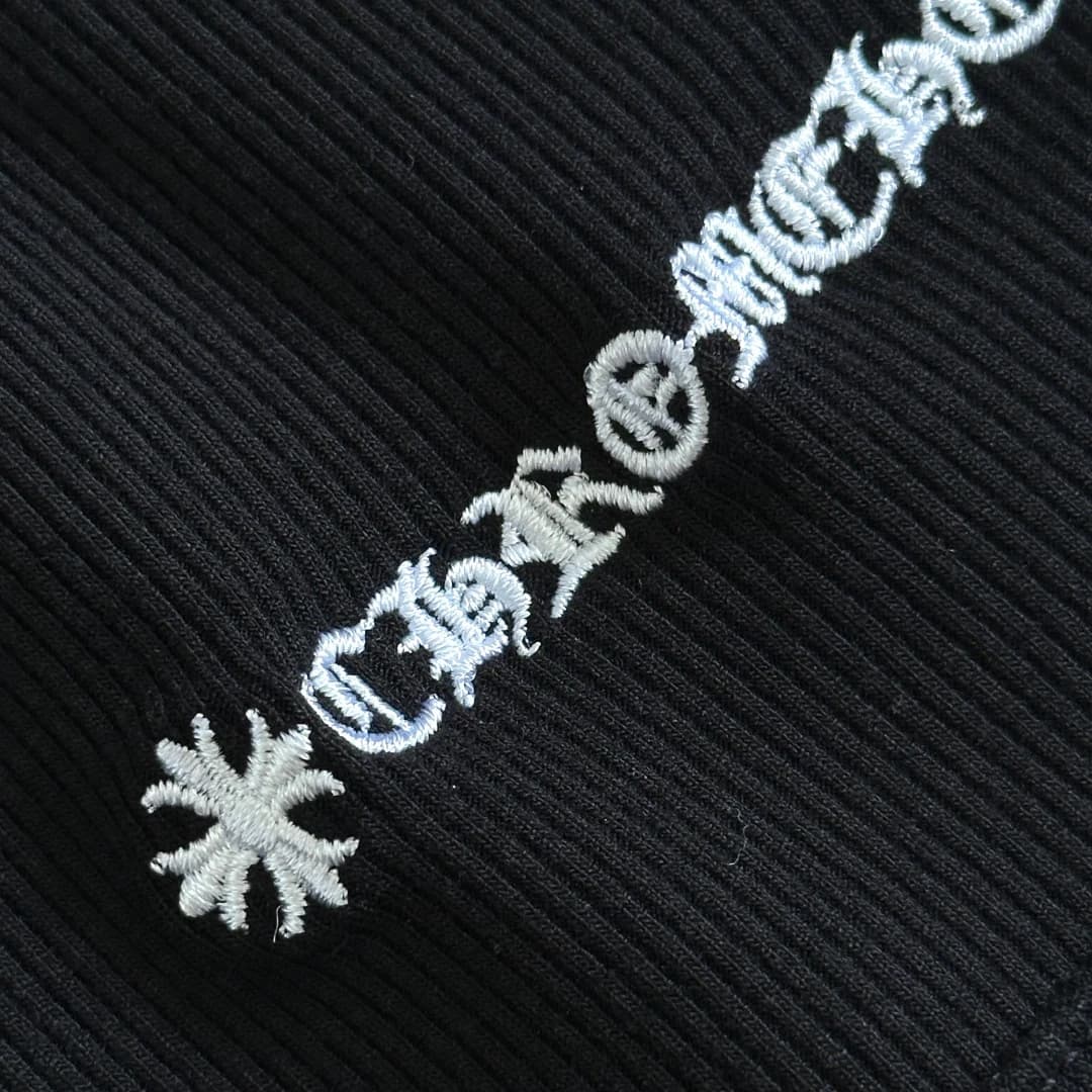 Деталь белой готической вышивки Chrome Hearts на чёрной трикотажной ткани
