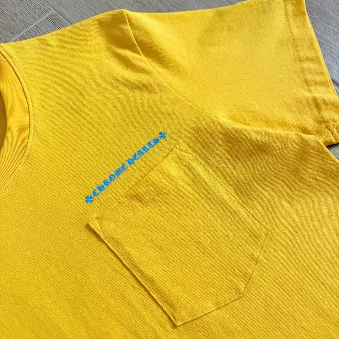 Нагрудный карман жёлтой футболки с голубой надписью Chrome Hearts