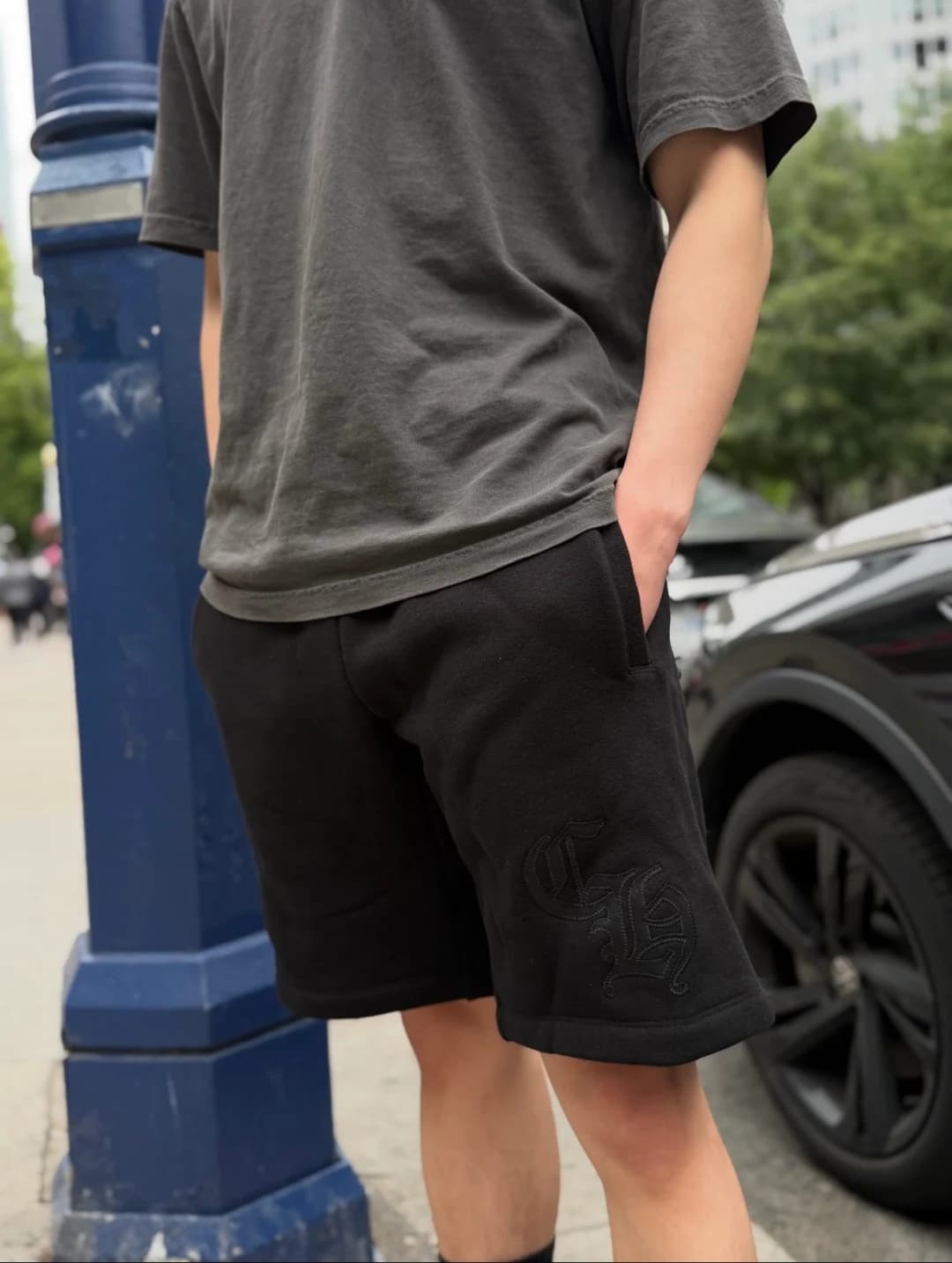 Чёрные шорты с вышивкой CH на модели на улице, ракурс сбоку