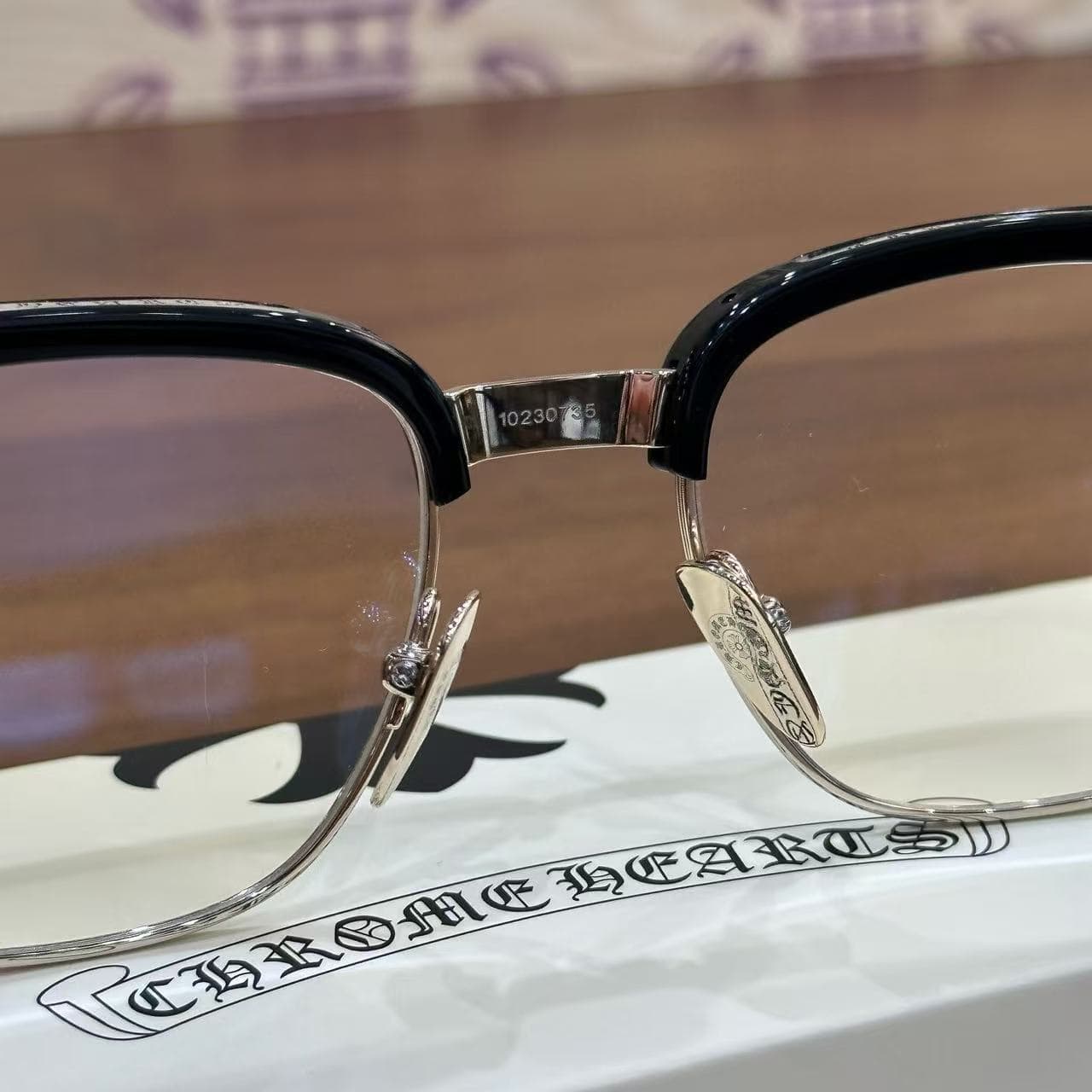 Крупный план моста оправы и металлических носоупоров с гравировкой Chrome Hearts