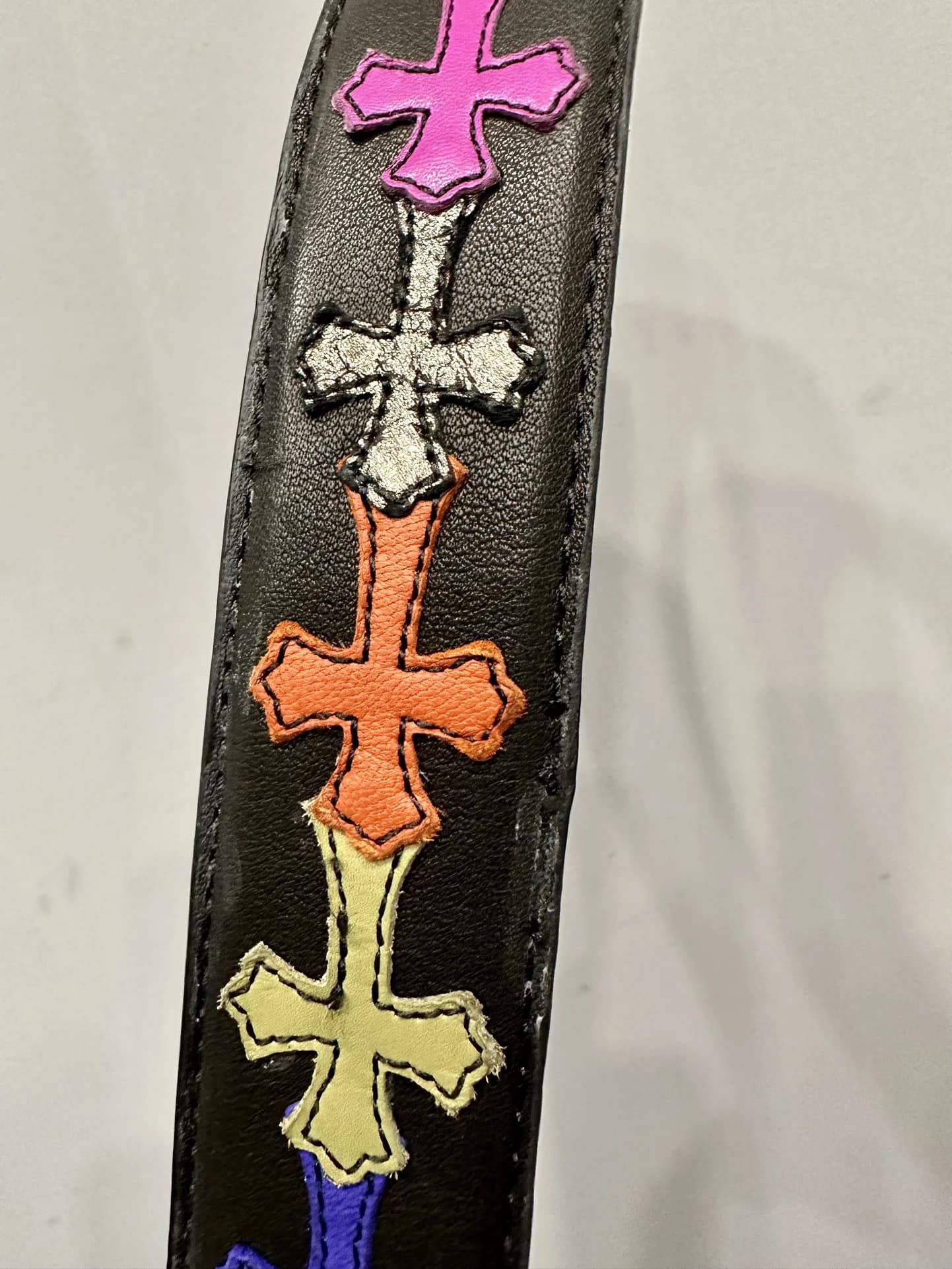 Деталь разноцветных кожаных нашивок в форме крестов на ремне Chrome Hearts