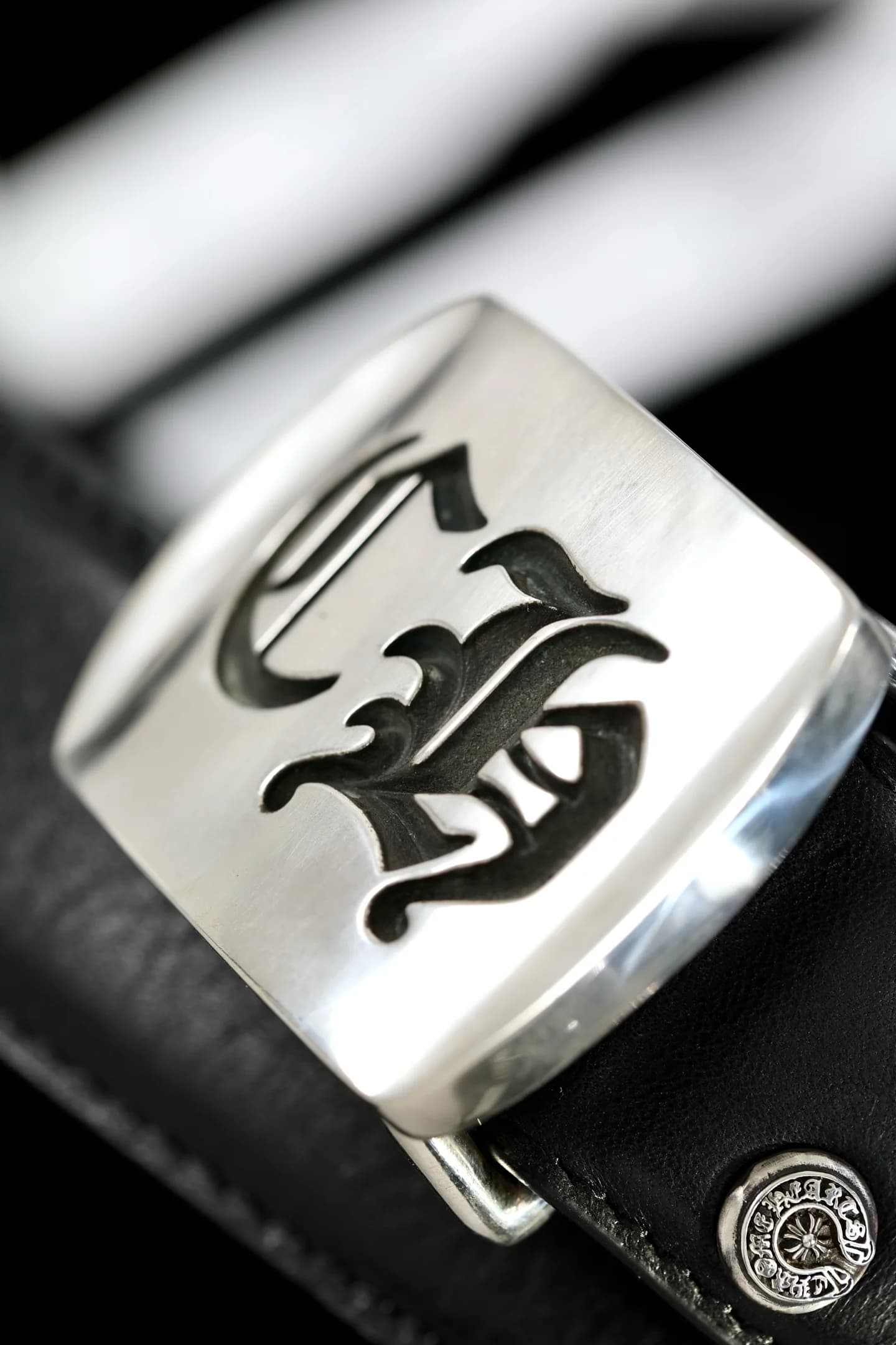 Крупный план серебряной пряжки Chrome Hearts с готической монограммой CH