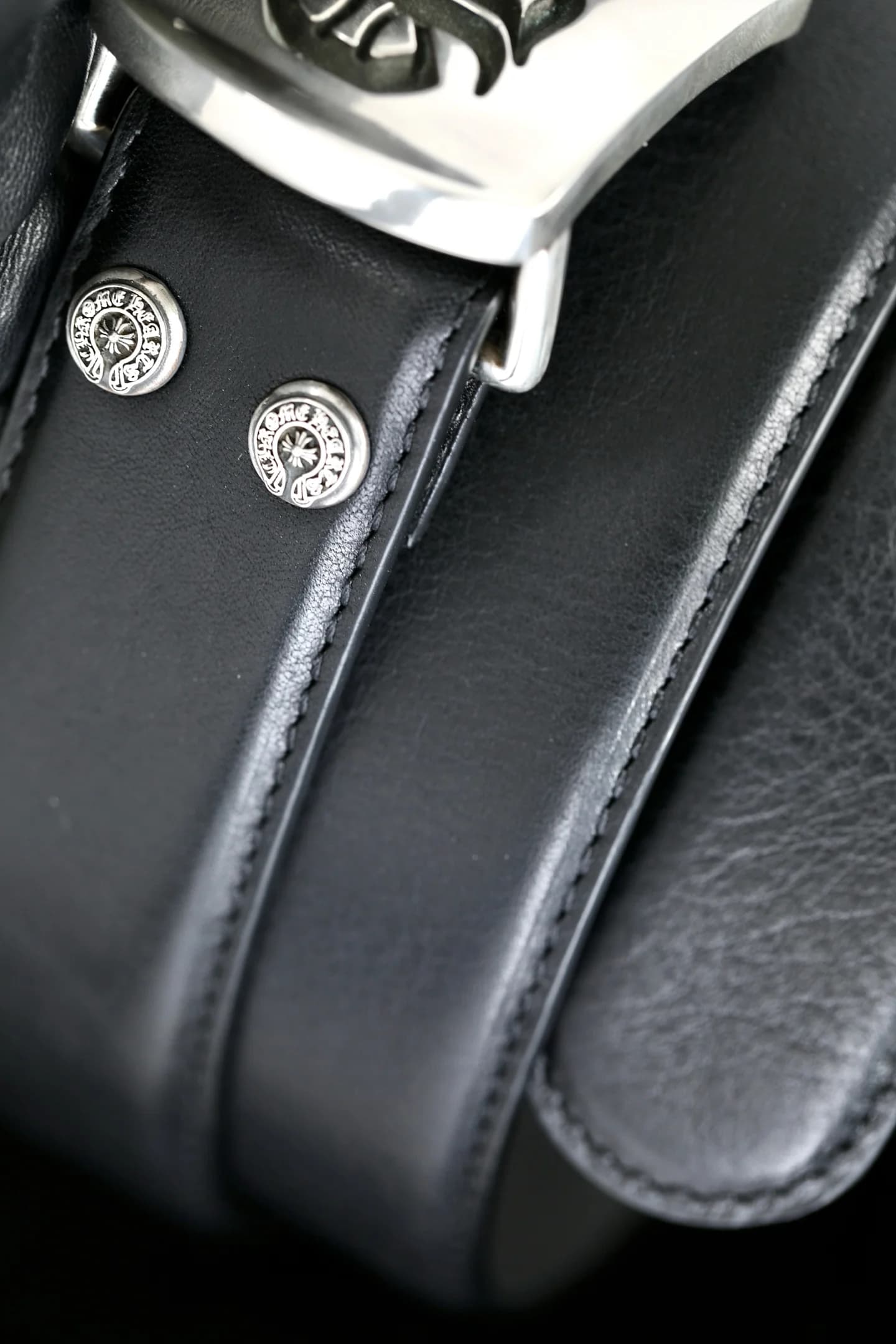 Детали кожаной строчки и серебряных кнопок-заклепок ремня Chrome Hearts