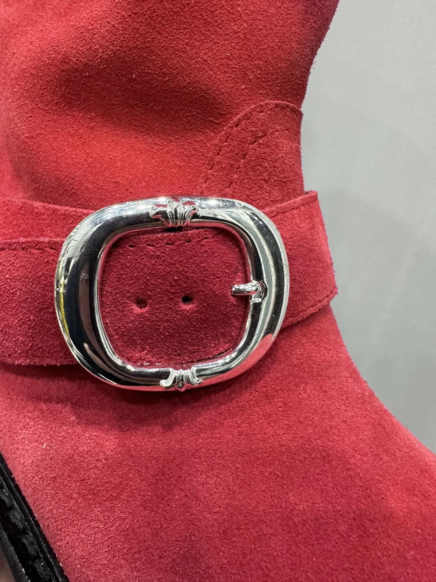 Деталь серебряной пряжки на красном замшевом сапоге Chrome Hearts x Wesco