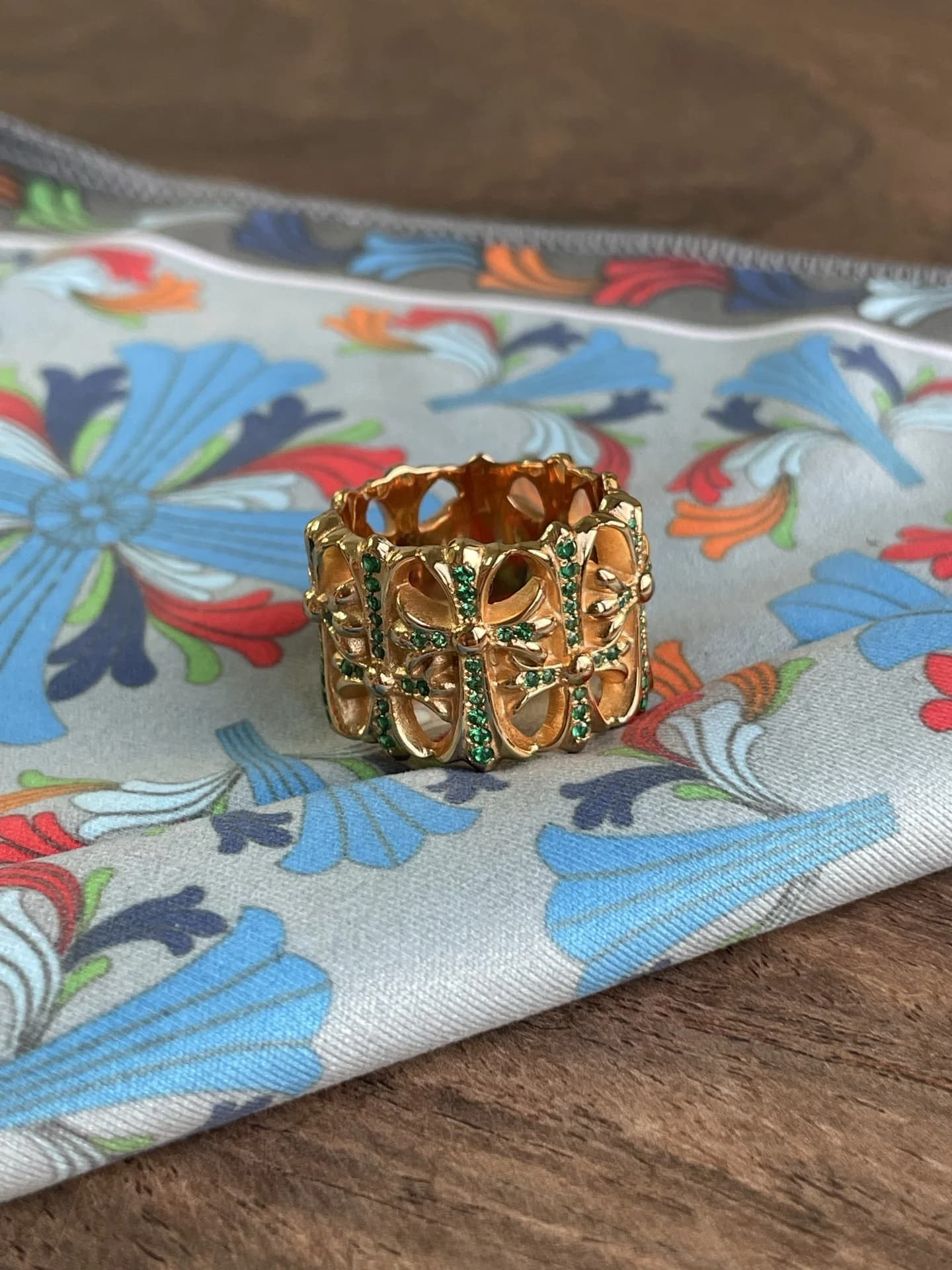 Фронтальный ракурс кольца Chrome Hearts Cemetery из жёлтого золота 22K с паве из зелёных камней