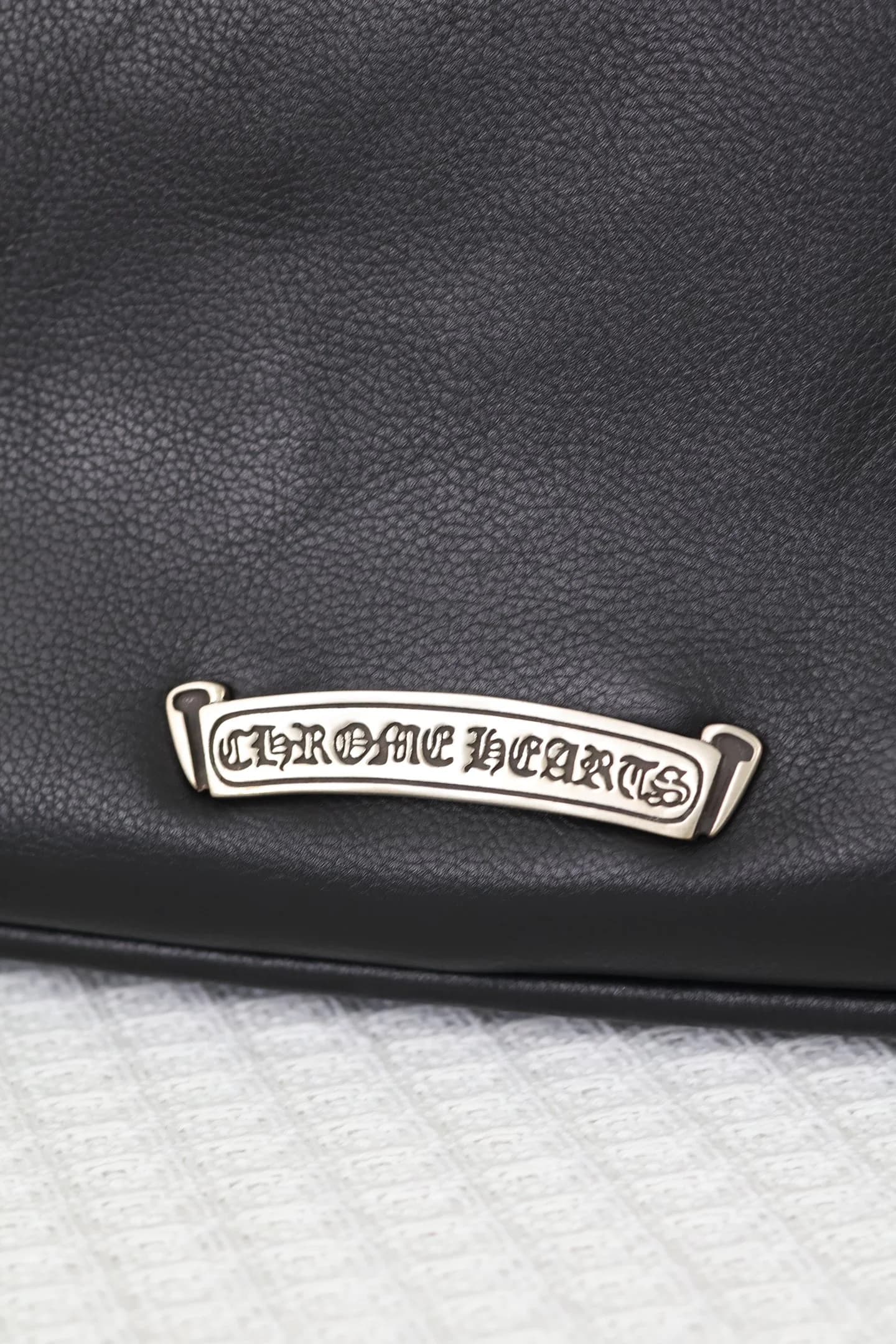 Крупный план серебряной плашки с фирменным логотипом Chrome Hearts
