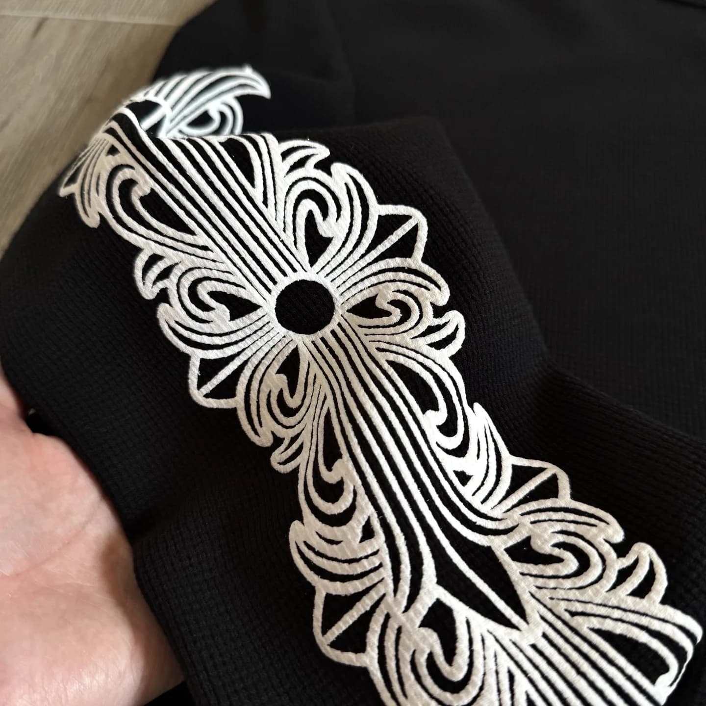 Деталь готического принта на рукаве лонгслива Chrome Hearts