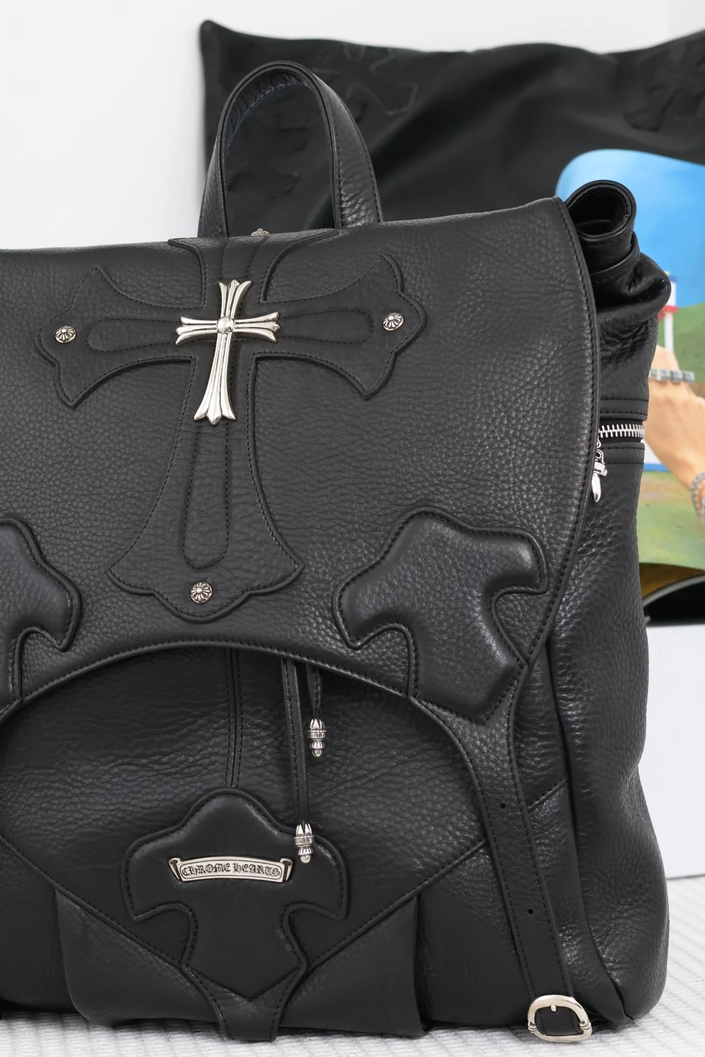 Крупный план клапана рюкзака Chrome Hearts с серебряным крестом и кожаными нашивками
