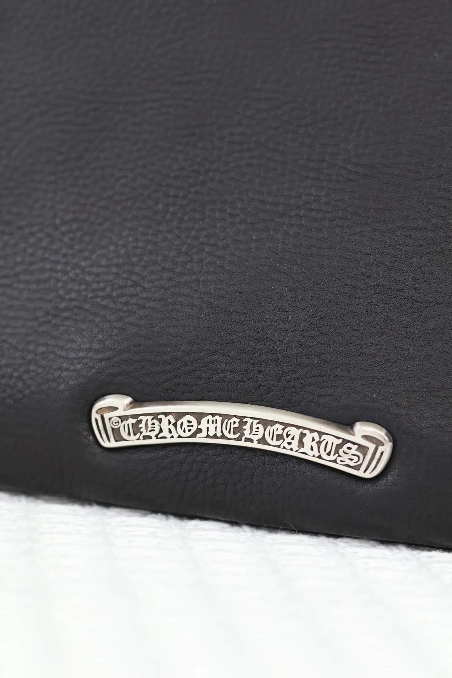 Крупный план серебряной плашки с гравировкой Chrome Hearts